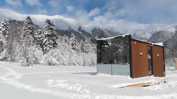 Vista aérea de uma casa inovadora de alta tecnologia com paredes espelhadas em meio a uma floresta de inverno nas montanhas. O conceito de ecoturismo nas montanhas. Arquitetura moderna em reservas naturais — Vídeo de Stock