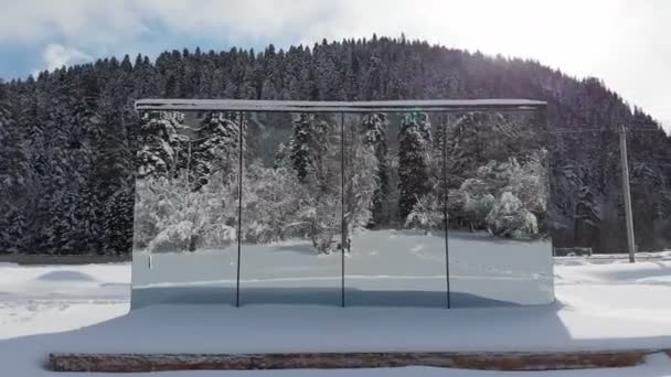 Vista aérea de uma casa inovadora de alta tecnologia com paredes espelhadas em meio a uma floresta de inverno nas montanhas. O conceito de ecoturismo nas montanhas. Arquitetura moderna em reservas naturais — Vídeo de Stock