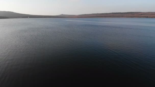 Vue aérienne depuis un drone volant à basse altitude sur la surface lisse du drone le soir après le coucher du soleil. Vidéo de fond avec plan d'eau naturel local