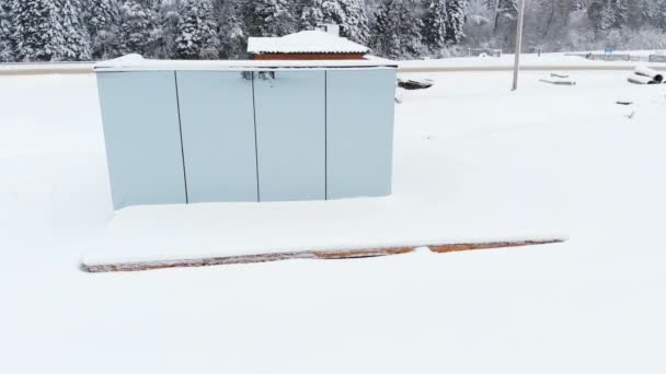 Vista aérea de una innovadora casa de alta tecnología con paredes transparentes espejadas en invierno cerca de un bosque de coníferas en las montañas del Cáucaso o los Alpes. — Vídeo de stock