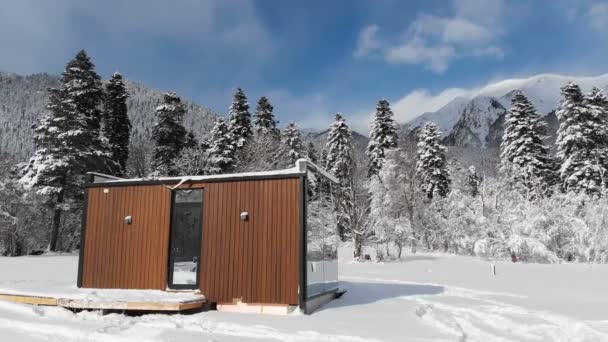 Flygfoto av ett innovativt högteknologiskt hus med speglade väggar mitt i en vinterskog i bergen. Begreppet ekoturism i bergen. Modern arkitektur i naturreservat — Stockvideo