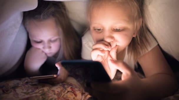 Zwei kleine Mädchen mit Matratzen schlafen nicht unter einer Decke. Schlaflosigkeit bei Kindern und Internetsucht nach Geräten und Gadgets — Stockvideo