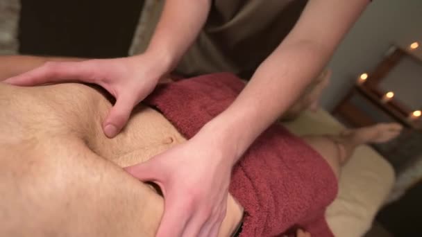 Un hombre masajeador fisioterapeuta activa un masaje de diafragma a un atleta masculino cliente muscular. Primer plano. Pequeña profundidad de campo — Vídeo de stock