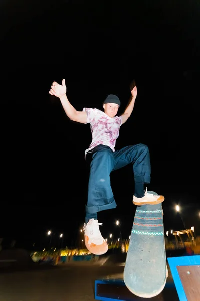 Ein junger Skater schafft das Kunststück, nachts in einem Skatepark zu rutschen. Das Konzept der nächtlichen Freizeit und Jugendkultur in der Nacht — Stockfoto