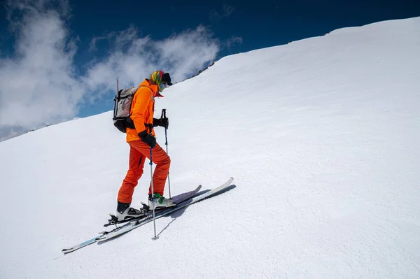 Un esquiador con un traje naranja esquía en una montaña fuera de pista esquiando en el Cáucaso norte del Monte Elbrus — Foto de Stock