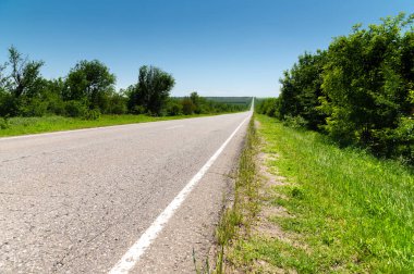 Yazın asfalt yolda yol kenarlarında mavi gökyüzüne karşı yeşil çimenler ve ağaçlar vardı. Ulaşım ve ulaşım lojistik şirketleri için güneşli bir gün.