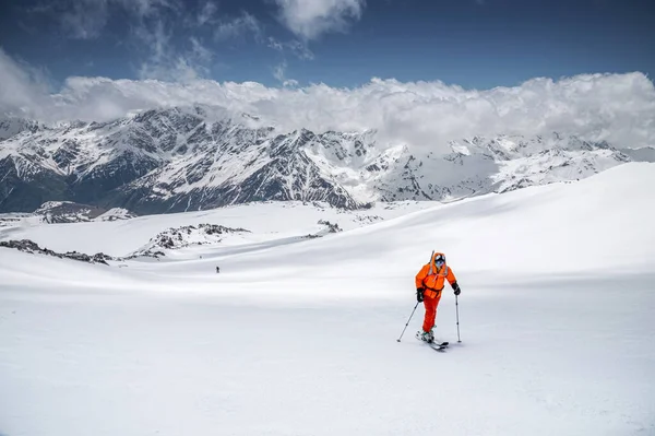 Um esquiador em um esquis de terno laranja em uma montanha off-piste esqui no norte do Cáucaso do Monte Elbrus — Fotografia de Stock