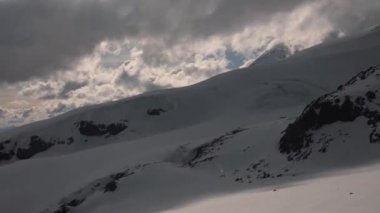 Günbatımından sonra Kuzey Kafkasya üzerindeki bulutlar deniz seviyesinden yüksek buzulları ve dağları kaplar. Dağlarda bulutların hareket zamanı.