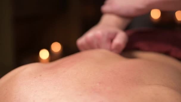 Ung man massör gör sport massage till en muskulös idrottsman. Professionell ryggmassage i ett mörkt rum med ljus. Muskelapparatens avslappning och spaåterhämtning — Stockvideo