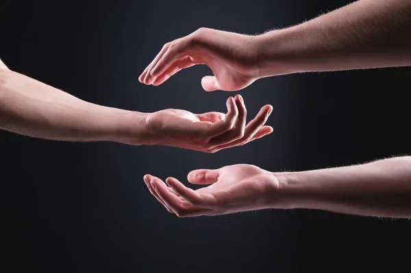 ケアと黒の背景に手を助けるのクローズアップ。手の概念の象徴を支援し支援する — ストック写真