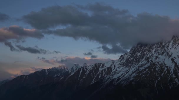 Timelapses van hoge besneeuwde bergen en wolken hoog in de bergen van de noordelijke Kaukasus na zonsondergang. De laatste zonnestralen op de bergen van het begin van de nacht — Stockvideo