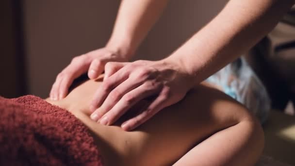 Massagem profissional das costas e parte inferior das costas. Massagem de massagista masculino um cliente para uma mulher em um quarto escuro à luz de velas — Vídeo de Stock