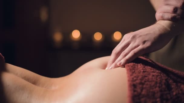 Gros plan main masculine d'un masseur physiothérapeute professionnel faisant un massage lombaire à une patiente dans une chambre de luxe de massage avec une lumière tamisée — Video