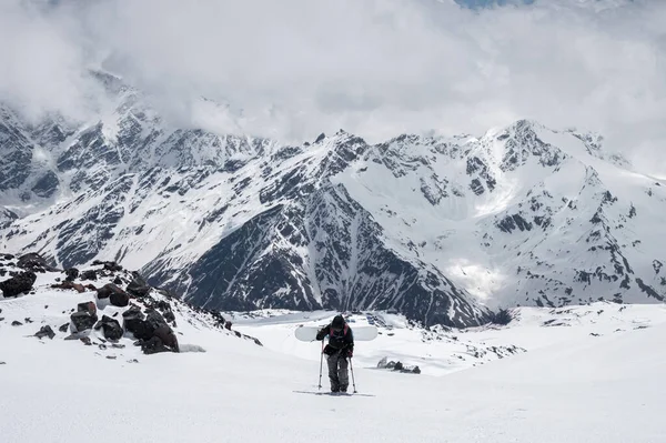 Mulher snowboarder sobe a montanha através da neve sertão com um snowboard atrás de seus ombros. Suba a montanha para freeride — Fotografia de Stock