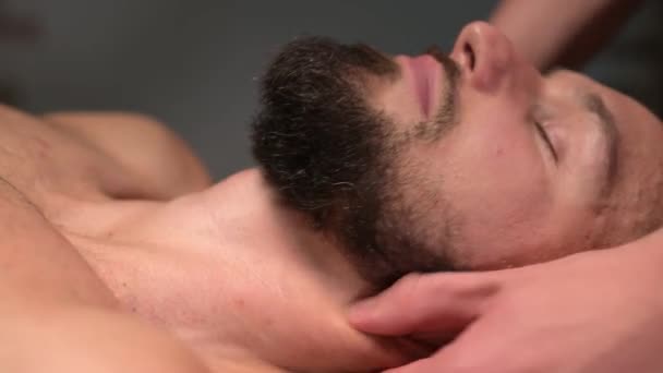 En manlig massageterapeut gör en klient idrottsman en man en hals massage i en mörk mysig spa massage salong. Professionell idrottsmassage — Stockvideo