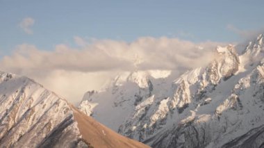 Günbatımı zamanı yüksek dağlarda. Kasırga bulutlarının önü bulutlu. Kayalık sırt arkaplanından hava durumu tahminleri geliyor.