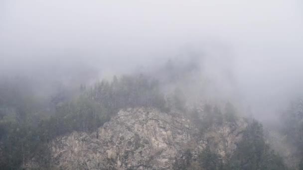 Tiden går branta bergssluttningar täckta med evigt grön skog och pudrade med snö på vilket låga moln flyter. 4K moln rörelse i bergen — Stockvideo