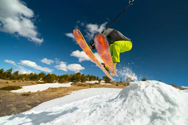 Žena lyžař sportovec dělá skok v letu na zasněženém svahu na pozadí modré oblohy hor a mraků. Freeride a extrémní lyžování pro ženy — Stock fotografie