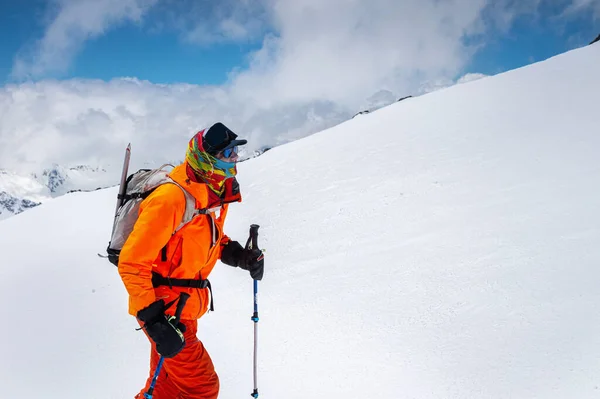 Retrato de um escalador de popa esquiador em óculos de sol e um boné com uma máscara de esqui em seu rosto. contra o pano de fundo do Monte Elbrus — Fotografia de Stock