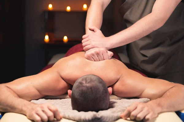 Rückenmassage. Männlich masseur tun rückenmassage bis männlich client im dunkel raum von spa salon — Stockfoto