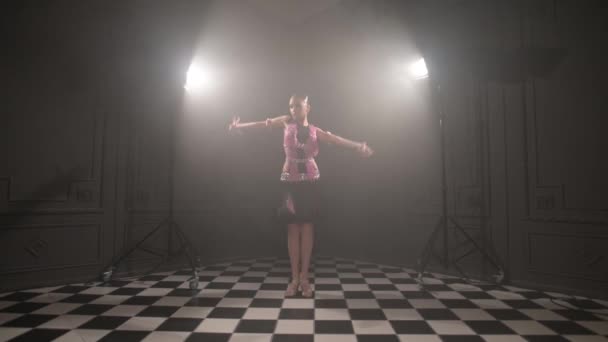 Aantrekkelijk tiener meisje in een mooie roze zwarte jurk professioneel dansen ballroom sport dans sambu latino amerikaanse dansen in een donkere kamer gevuld met rook — Stockvideo