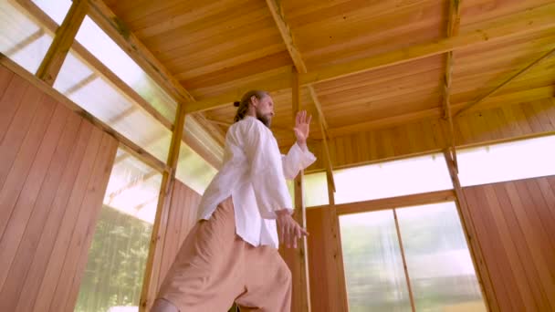 Gebaarde blanke man met witte kleren om concentratie en ademhaling te oefenen voordat hij Qigong tai chi beoefent — Stockvideo