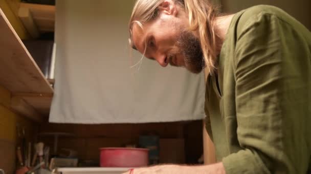 Mannelijke handen die een kleikom maken op een pottenbakkerswiel. Ambachten en productie van exclusieve theewaren van klei — Stockvideo