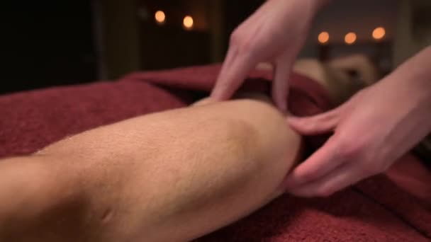 Крупный план профессионального массажа колен и тазобедренного сустава. Мужской массажист делает массаж клиенту-мужчине — стоковое видео
