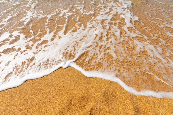 Zeegolf met wit schuim op geel goudkleurig zand. Zomer oceaan vakantie achtergrond — Stockfoto