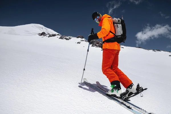 Ein Skifahrer im orangefarbenen Anzug auf Skiern abseits der Piste im nördlichen Kaukasus am Elbrus — Stockfoto