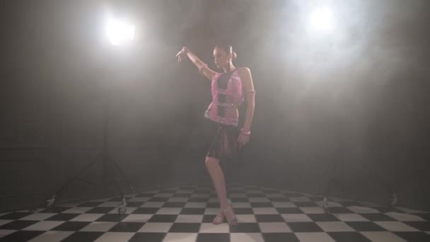 Aantrekkelijk tiener meisje in een mooie roze zwarte jurk professioneel dansen ballroom sport dans sambu latino amerikaanse dansen in een donkere kamer gevuld met rook — Stockvideo