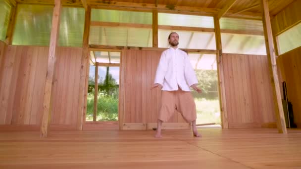 Gebaarde blanke man met witte kleren om concentratie en ademhaling te oefenen voordat hij Qigong tai chi beoefent — Stockvideo