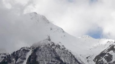 Bulutların üzerinde yüzdüğü karlı dağların tepelerine yakın çekim zamanı. Dağ hava tahmini