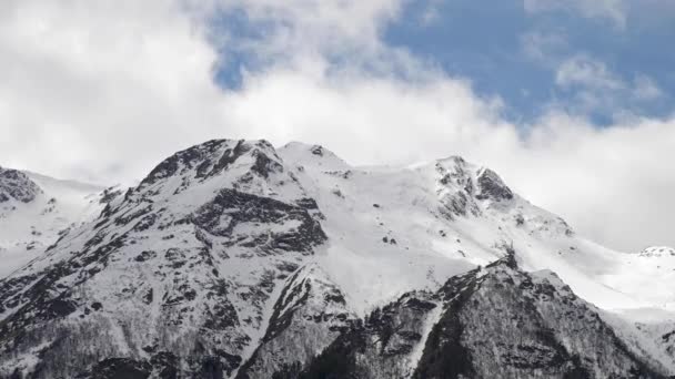 Timelapse zbliżenie wierzchołków gór pokrytych śniegiem, na których chmury pływają. Prognoza pogody dla gór — Wideo stockowe