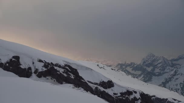 4K, Kuzey Kafkasya 'nın karla kaplı zirvelerindeki dağların yükseklerindeki bulutların hareketini hızlandırır. — Stok video
