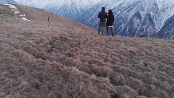 Vista aérea de un hombre y una mujer de pie en lo alto de las montañas y admirando la vista. Senderismo deportivo de montaña — Vídeo de stock