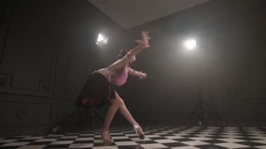 Güzel pembe elbiseli çekici genç kız profesyonel dansçı salon sporu sambu Latin Amerikalı dumanla dolu karanlık bir odada dans ediyor.
