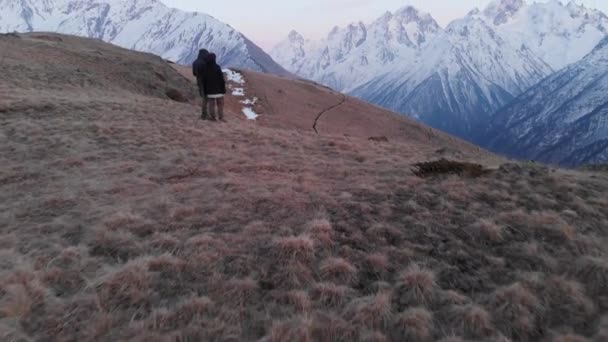 Vista aérea de un hombre y una mujer de pie en lo alto de las montañas y admirando la vista. Senderismo deportivo de montaña — Vídeo de stock