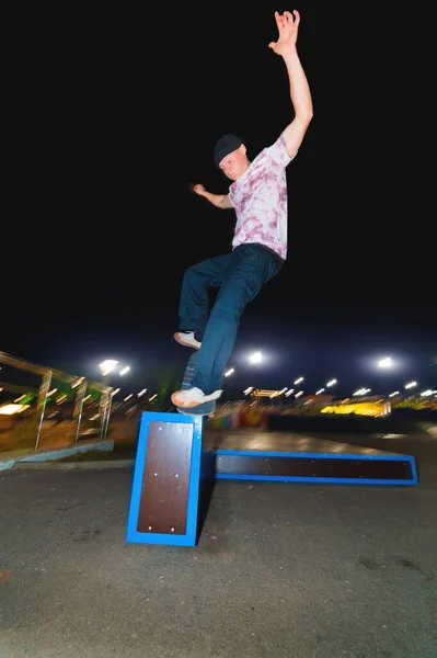 Mladý bruslař dělá trik skluzavka na zábradlí ve skateparku v noci — Stock fotografie