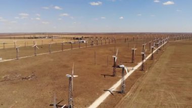 Rüzgar türbinlerinin hava görüntüsü sarı alanlar arasında temiz rüzgar enerjisi üretiyor. Rüzgârlı bozkırlarda yenilenebilir enerji üretimi.
