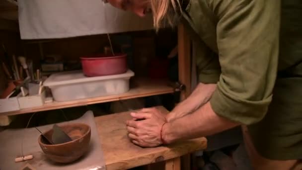 Man pottenbakker kneden klei verslaat het voor installatie op een pottenbakkerswiel — Stockvideo