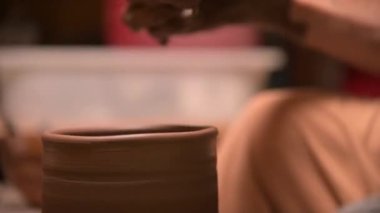 Çömlekçi bir adamın çömlekçinin kilden bir çanak çömlek yapmasını yakından çek.