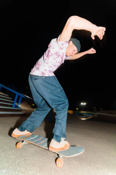 一个年轻的滑板手晚上在一个滑板公园里做的把戏在栏杆上。X光文化夜生活概念 — 图库照片