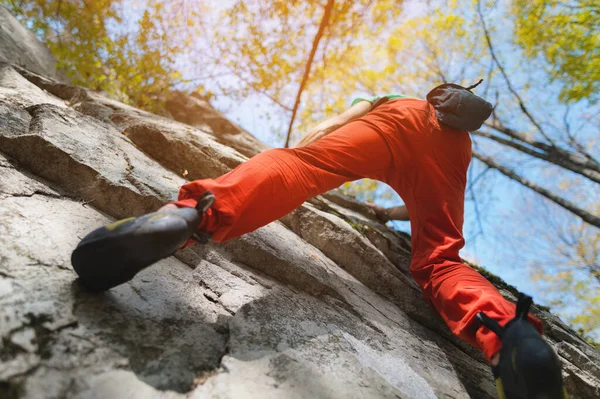 Свободный пожилой мужчина-альпинист висит на каменной стене в лесу в горах. Зрелая спортивная концепция — стоковое фото