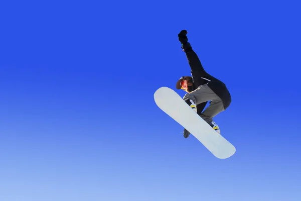 Snowboarder robi chwytliwą sztuczkę skoku na błękitne niebo. Niebieskie gradientowe tło pojedynczego sportowca w locie — Zdjęcie stockowe