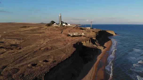 Un faro típico a rayas en la costa de la zona de la estepa por la noche. Vista aérea empinada de la costa — Vídeos de Stock