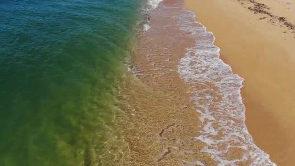 Vista aérea close-up voo baixo sobre as ondas do mar rolando na costa de areia dourada. Acalme-se surfe atrás da praia da concha — Vídeo de Stock