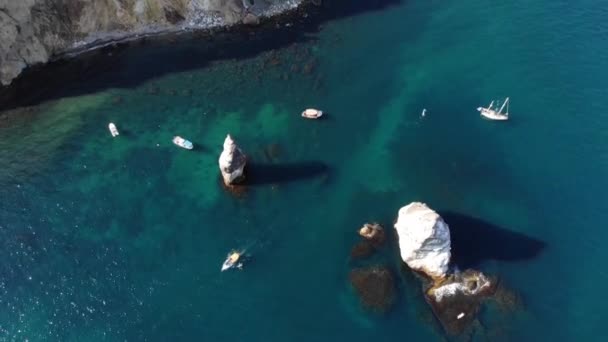 Luchtfoto van de rotskust van de baai met losse rotsen en boten met toeristen die er omheen zwemmen. Turkoois oceaan water in de kuststrook — Stockvideo
