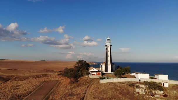 Un faro típico a rayas en la costa de la zona de la estepa por la noche. Vista aérea empinada de la costa — Vídeos de Stock