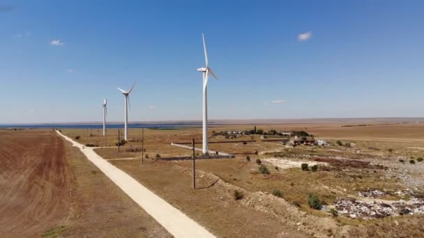 Veduta aerea delle turbine eoliche che generano energia eolica pulita tra i campi gialli. Produzione di energia rinnovabile nelle regioni delle steppe eoliche. — Video Stock